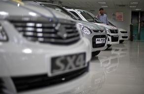 A sales executive speaks on his mobile phone as he stands in between Maruti Suzuki cars inside a showroom in New Delhi April 9, 2013. India